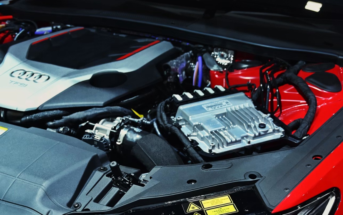 Audi engine bay showing supercharged motor with red valve cover and silver intake manifold