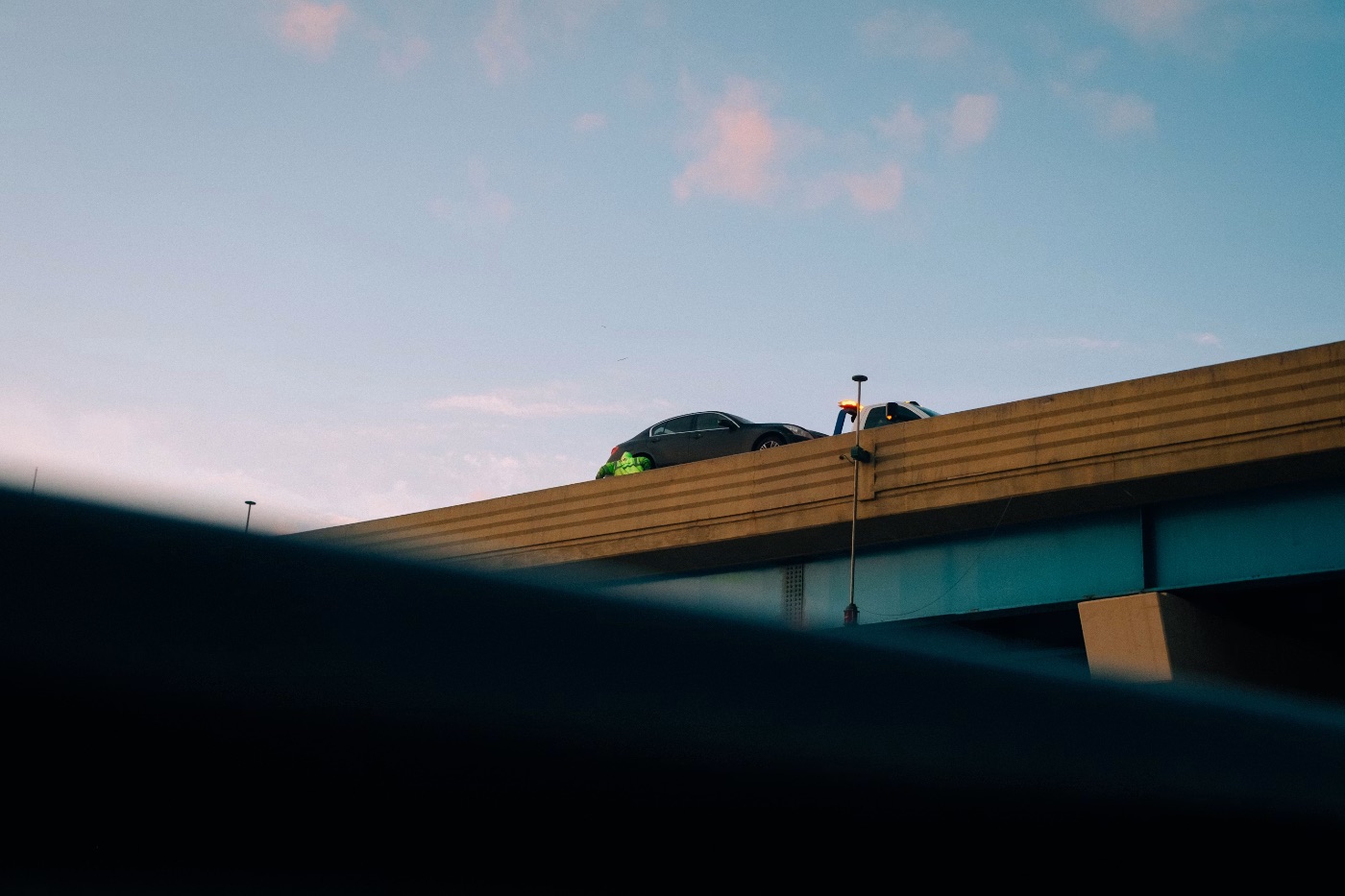 Dark sedan with green cargo on wooden rooftop structure against blue sky